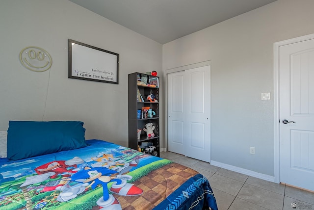 bedroom featuring light tile patterned floors, baseboards, and a closet