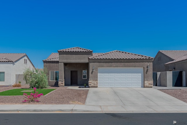 view of front of home featuring driveway, a tile roof, an attached garage, stone siding, and stucco siding