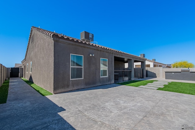 back of property featuring a patio, central AC, stucco siding, and fence