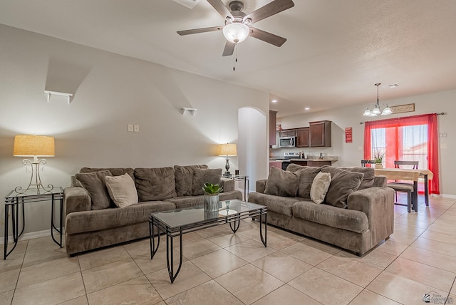 living area with baseboards, ceiling fan with notable chandelier, light tile patterned floors, and visible vents