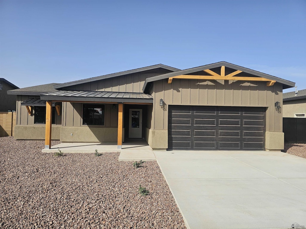 view of front facade with covered porch, a standing seam roof, metal roof, driveway, and a garage