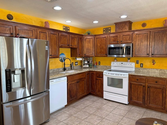 14551 E 49th St, Yuma, AZ 85367 - kitchen with brown cabinetry, recessed lighting, a sink, appliances with stainless steel finishes, and light tile patterned floors