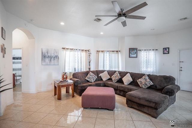 living area featuring arched walkways, a ceiling fan, light tile patterned flooring, and visible vents