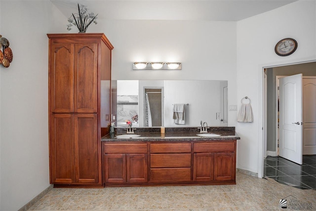 full bathroom with a sink, baseboards, walk in shower, and double vanity