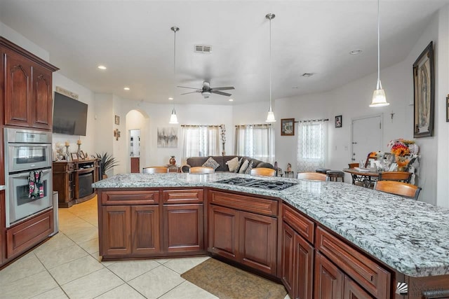 kitchen featuring visible vents, a ceiling fan, arched walkways, appliances with stainless steel finishes, and light tile patterned floors