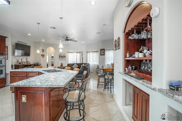 kitchen with a kitchen breakfast bar, arched walkways, light tile patterned floors, open floor plan, and recessed lighting