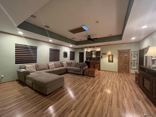 home theater with a raised ceiling, a skylight, ceiling fan, and hardwood / wood-style flooring