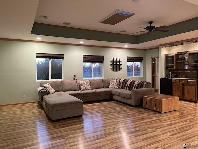 living room featuring a tray ceiling, crown molding, ceiling fan, and light hardwood / wood-style floors