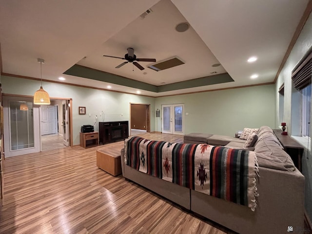 bedroom with ceiling fan, crown molding, light hardwood / wood-style flooring, and a tray ceiling