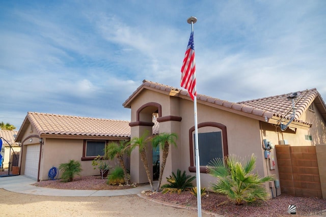 mediterranean / spanish-style home with an attached garage, stucco siding, and a tile roof