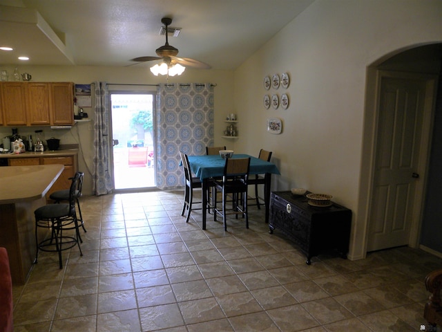 dining space with ceiling fan, visible vents, arched walkways, light tile patterned floors, and lofted ceiling