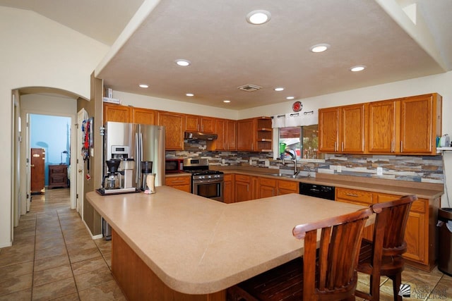 kitchen with under cabinet range hood, stainless steel appliances, a sink, and tasteful backsplash