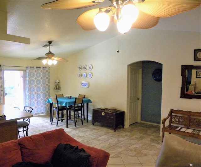 living room featuring vaulted ceiling, arched walkways, light tile patterned floors, and ceiling fan with notable chandelier