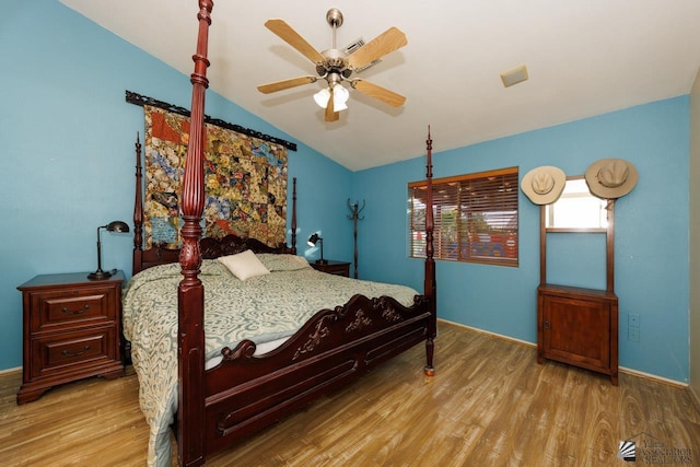 bedroom featuring baseboards, vaulted ceiling, wood finished floors, and visible vents