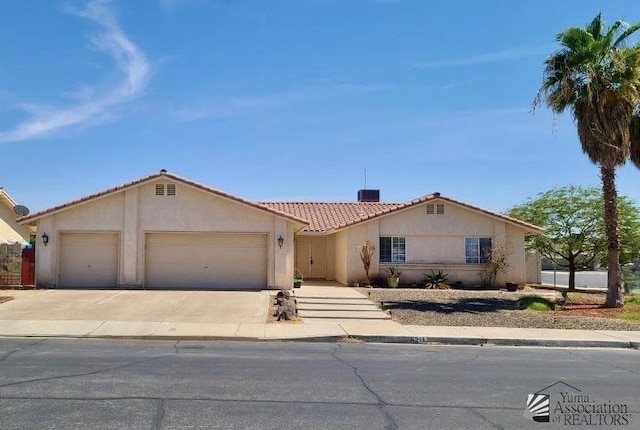 6311 E 42nd St, Yuma, AZ 85365 - view of front facade featuring a garage, a tile roof, stucco siding, and driveway