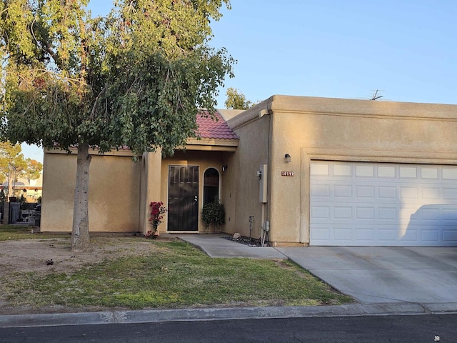 view of front of home featuring an attached garage, driveway, a tile roof, and stucco siding