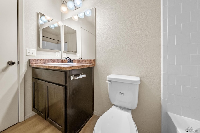 full bath with a bathing tub, toilet, wood finished floors, and vanity