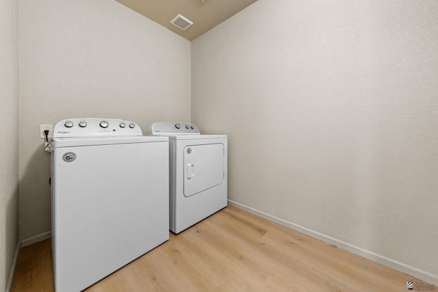 laundry room with laundry area, visible vents, washing machine and dryer, baseboards, and light wood-type flooring