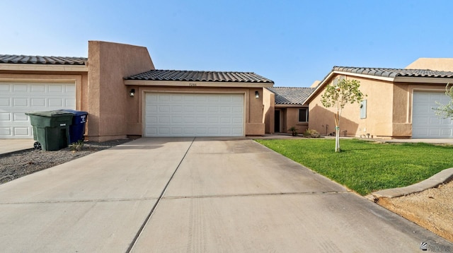 view of front facade with concrete driveway, a tile roof, a front yard, and stucco siding