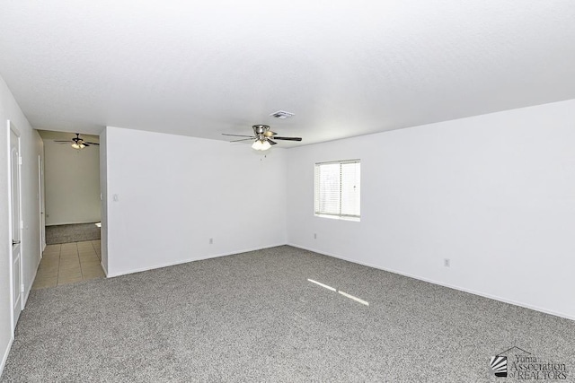 carpeted empty room with a ceiling fan, baseboards, and visible vents