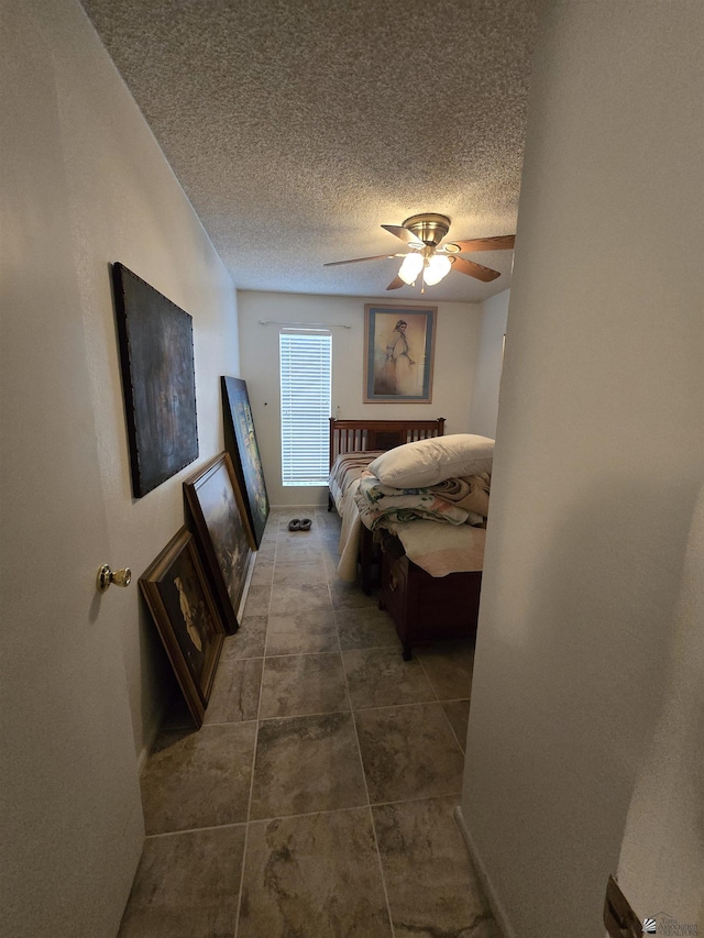 bedroom featuring a ceiling fan, a textured ceiling, and baseboards