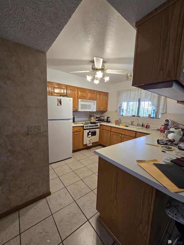 kitchen featuring white appliances, light countertops, a textured ceiling, a sink, and light tile patterned flooring