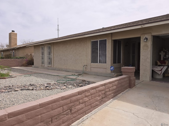 rear view of house featuring a patio area and stucco siding