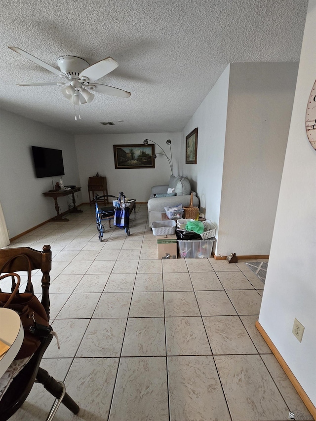 living room featuring a textured ceiling, baseboards, a ceiling fan, and light tile patterned flooring