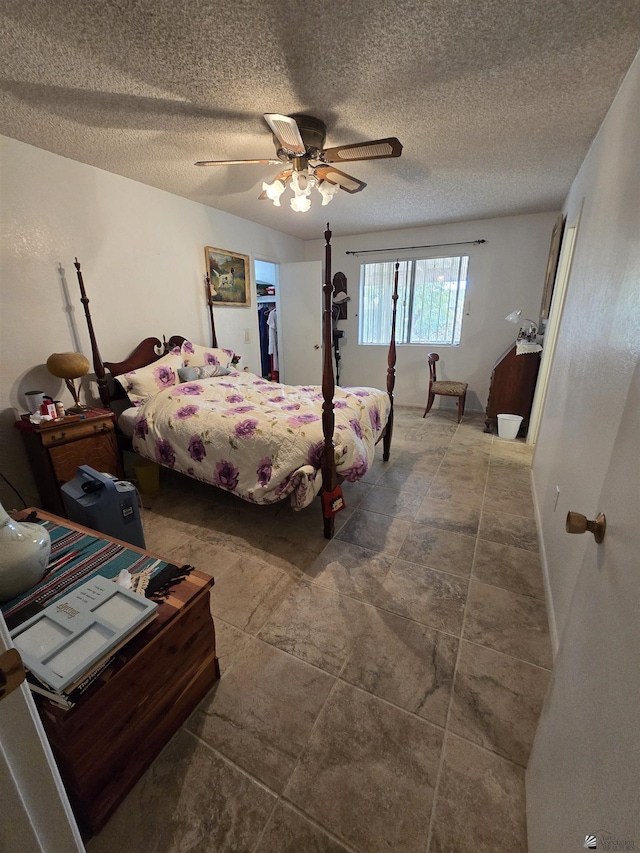 bedroom with ceiling fan, a spacious closet, and a textured ceiling