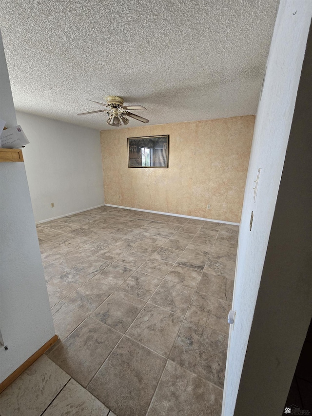 spare room featuring a ceiling fan, a textured ceiling, and baseboards