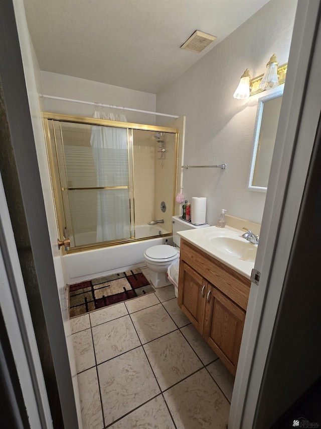 bathroom featuring bath / shower combo with glass door, visible vents, toilet, vanity, and tile patterned flooring