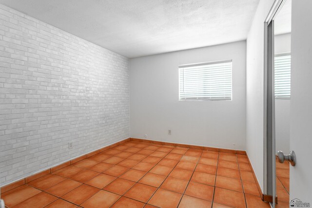 541 E Hacienda Dr, Yuma, AZ 85365 - empty room with brick wall, baseboards, and light tile patterned floors