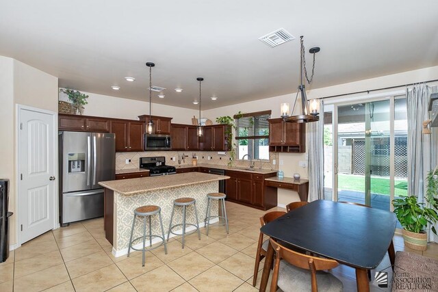 6588 E 35th Pl, Yuma, AZ 85365 - kitchen featuring appliances with stainless steel finishes, backsplash, light tile patterned flooring, a kitchen island, and recessed lighting