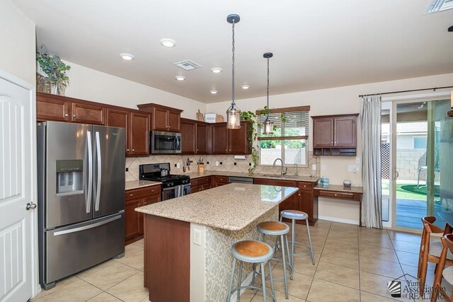 6588 E 35th Pl, Yuma, AZ 85365 - kitchen featuring appliances with stainless steel finishes, light tile patterned flooring, decorative backsplash, a kitchen island, and a breakfast bar