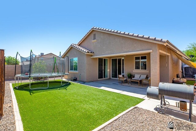 6588 E 35th Pl, Yuma, AZ 85365 - back of property featuring a trampoline, a patio area, stucco siding, a fenced backyard, and an outdoor hangout area