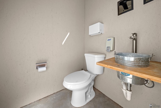 bathroom featuring a sink, concrete floors, and toilet