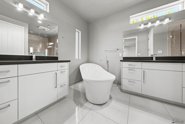 bathroom with baseboards, tiled shower, a freestanding bath, two vanities, and a sink