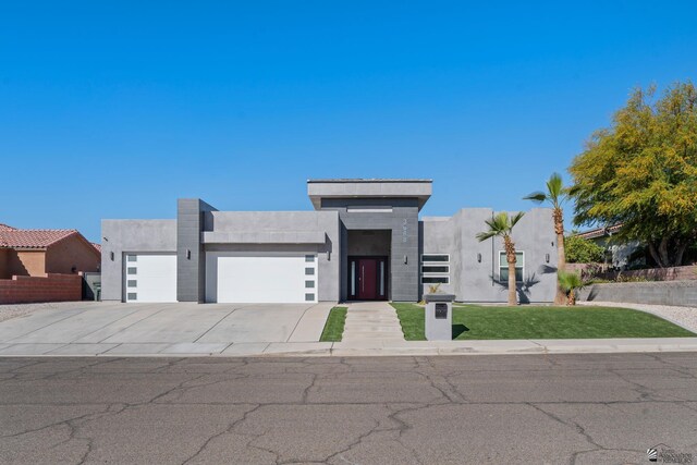 contemporary house with an attached garage, driveway, a front yard, and stucco siding