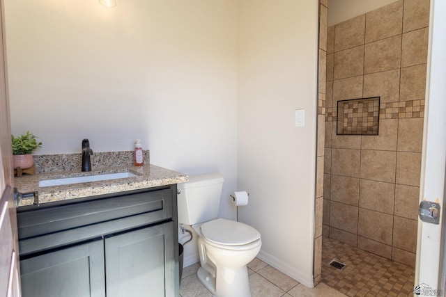 bathroom with vanity, baseboards, a tile shower, tile patterned floors, and toilet