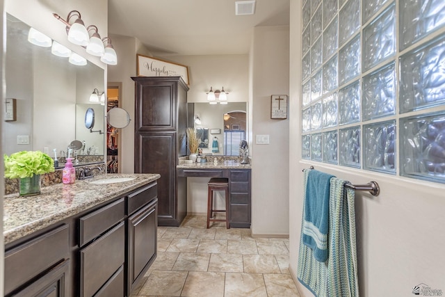 full bath with two vanities, visible vents, and a sink