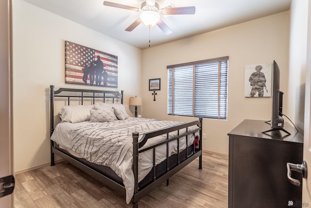 bedroom with light wood-style flooring, baseboards, and a ceiling fan