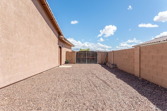 view of yard featuring a fenced backyard, driveway, and a gate