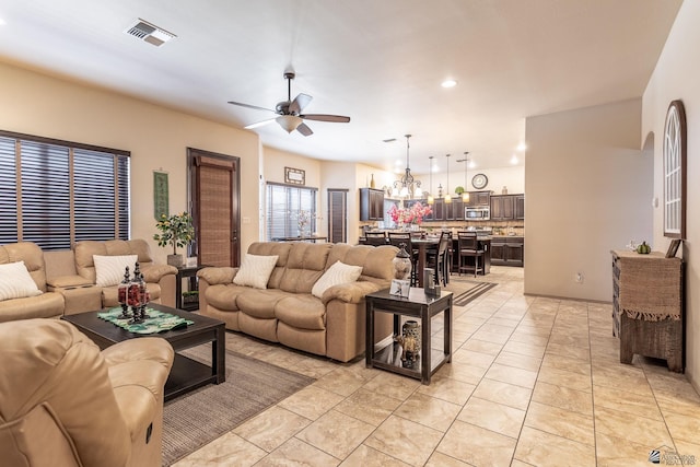 living room with light tile patterned flooring, visible vents, ceiling fan with notable chandelier, and recessed lighting