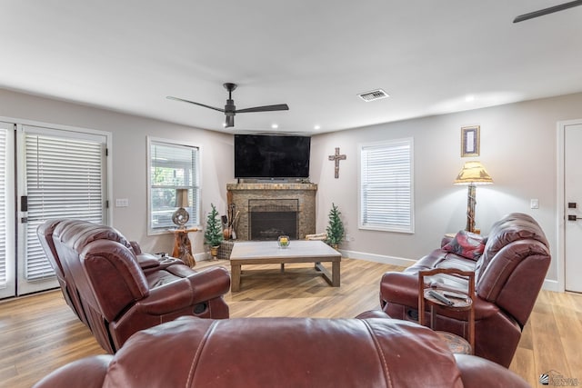 living room with ceiling fan, a fireplace, and light hardwood / wood-style flooring