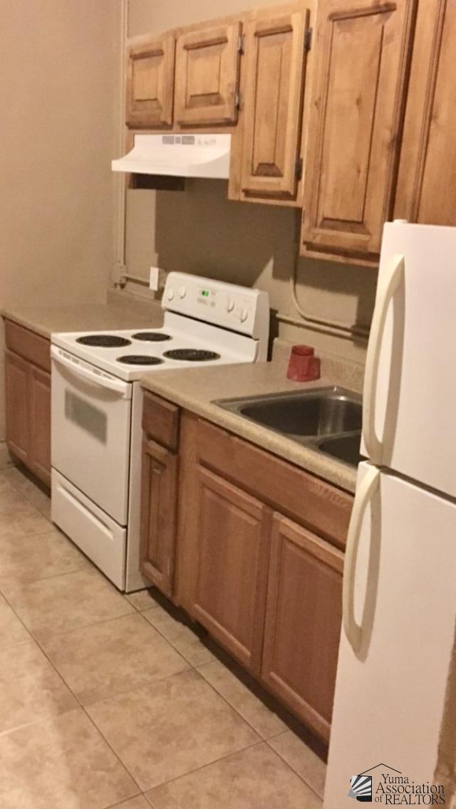 621 S Madison Ave, Yuma, AZ 85364 - kitchen featuring white appliances, under cabinet range hood, light countertops, and light tile patterned floors