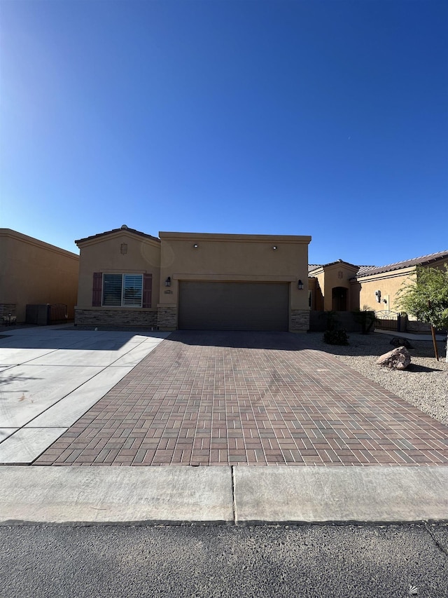 6143 E Morning Ln, Yuma, AZ 85365 - view of front facade featuring stucco siding, driveway, a garage, and stone siding