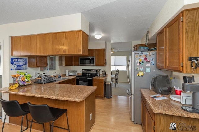 7442 E 24th Ln, Yuma, AZ 85365 - kitchen with stainless steel appliances, a peninsula, brown cabinets, and a textured ceiling