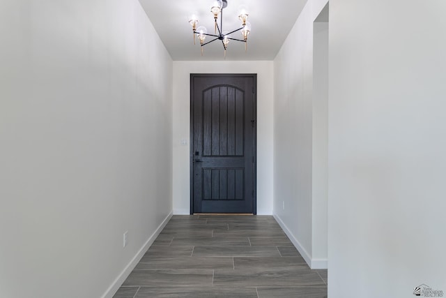 doorway featuring baseboards and a notable chandelier