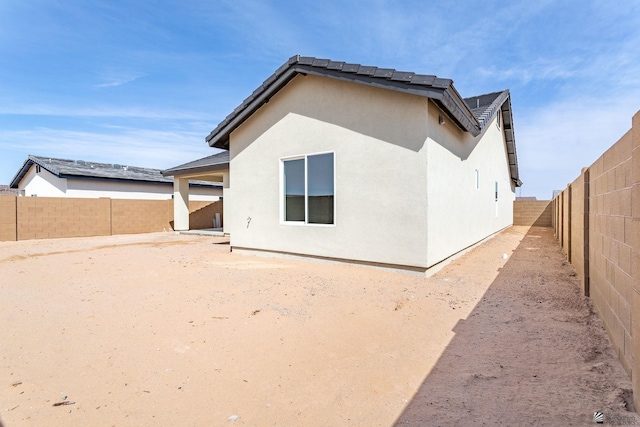back of property with a fenced backyard and stucco siding
