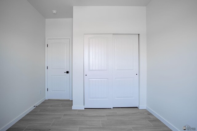 unfurnished bedroom with baseboards, wood tiled floor, and a closet